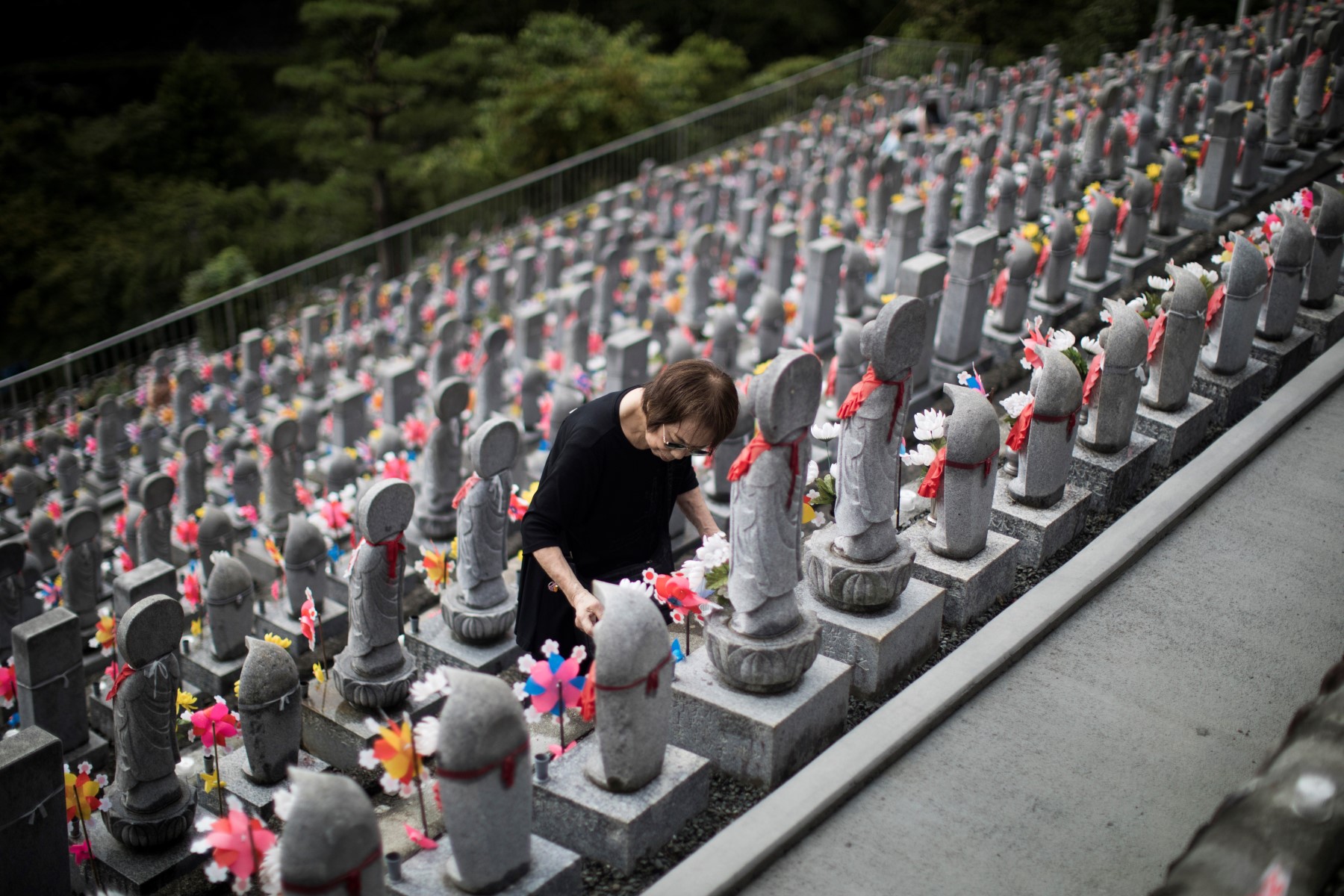 Một người phụ nữ thắp nến trước các bức tượng jizo trong chùa Phật giáo Jizoji ở Oganomachi, tỉnh Saitama, để cầu cho linh hồn của những đứa trẻ chưa chào đời hoặc những người đã chết khi còn trẻ, trong dịp Obon. Ảnh: AFP