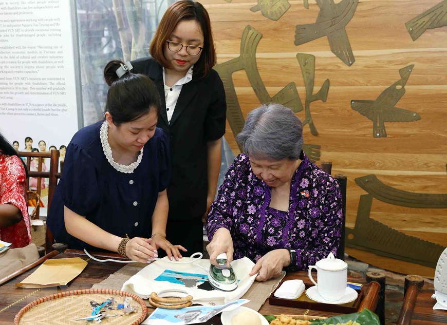 Bà Hà Tinh - Phu nhân Thủ tướng Singapore Lý Hiển Long trải nghiệm ghép tranh từ vải lụa vụn. Ảnh: TTXVN