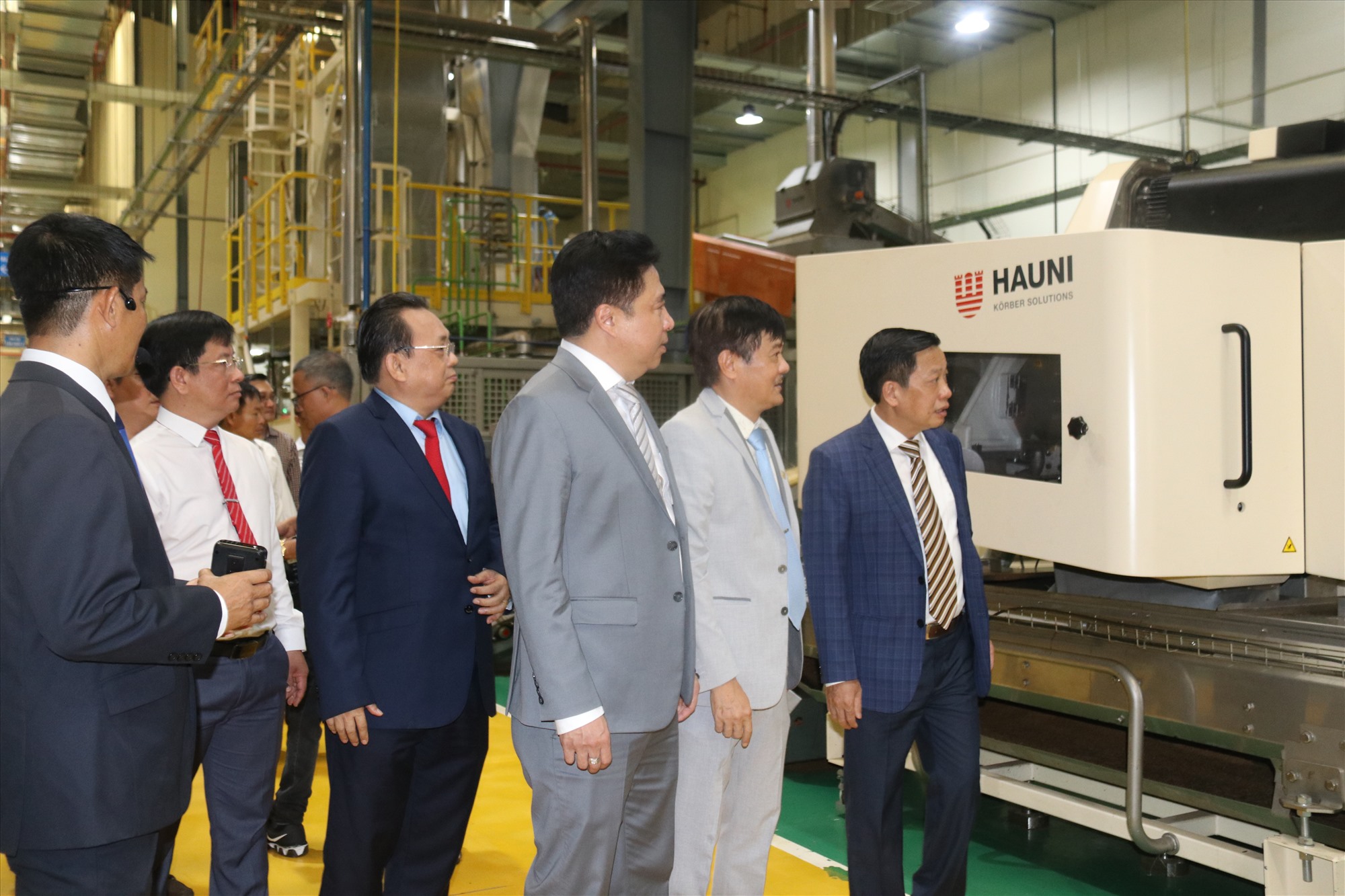 Lãnh đạo Tổng công ty Khánh Việt giới thiệu về dây chuyền sản xuất được nhà máy đầu tư mới hoàn toàn với công nghệ tự động hóa. Ảnh: Phương Linh