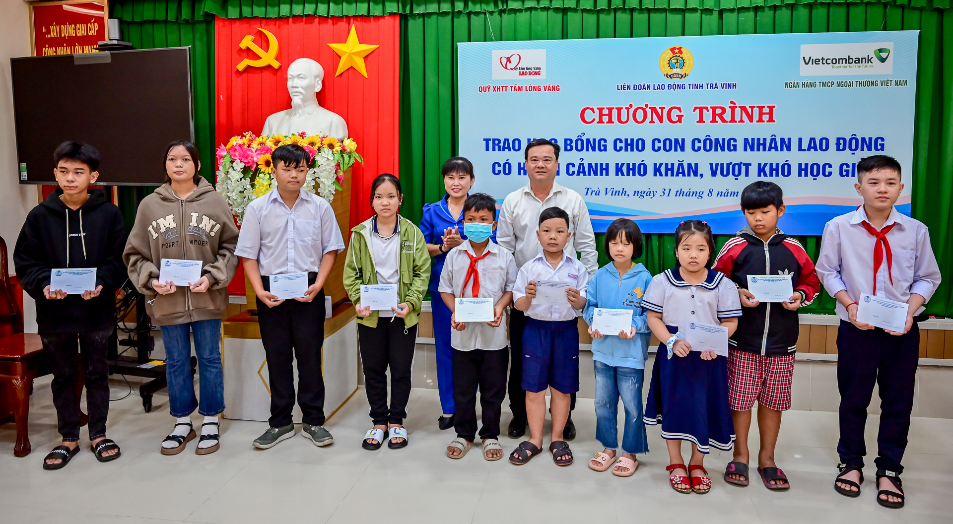 Lãnh đạo LĐLĐ tỉnh Trà Vinh cùng đại diện Quỹ XHTT Tấm lòng Vàng Lao Động và đại diện Vietcombank Trà Vinh trao học bổng cho học sinh. Ảnh: Đạt Phan