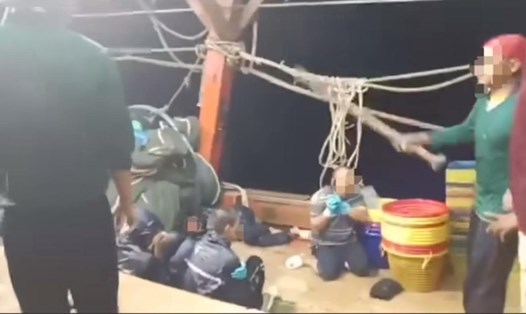 Thanh niên áo thun xanh dùng cây gỗ đánh 4 người trên tàu cá. Ảnh chụp từ clip