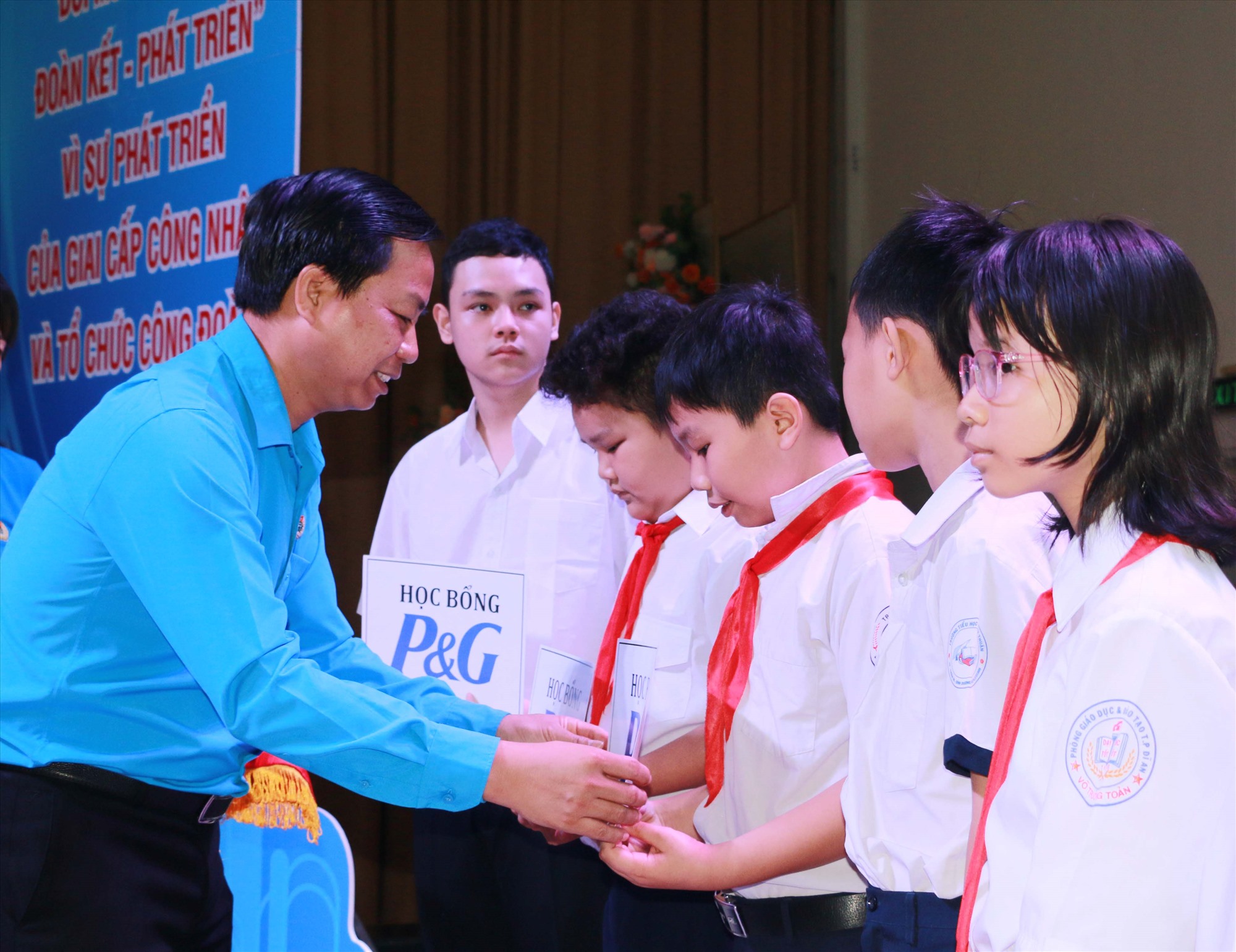 Ông Lưu Thế Thuận - Trưởng Ban Tuyên giáo Nữ công LĐLĐ tỉnh trao học bổng cho các em học sinh. Ảnh: Hoàng Trung