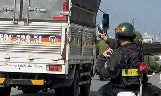 Cảnh sát rút súng thị uy yêu cầu tài xế xe tải dừng xe. Ảnh: Minh Châu