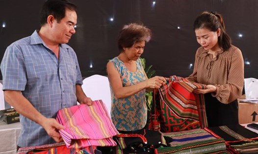 Bà Thị An Đê, Bù Đăng, Bình Phước (phải) giới thiệu sản phẩm thổ cẩm dân tộc thiểu số cho khách tham quan. Ảnh: TTXVN