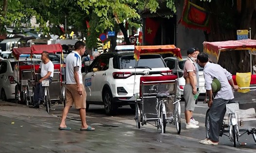 Một số chủ xe xích lô ngồi chờ khách ven Hồ Hoàn Kiếm vào chiều 25.9. Ảnh: Bích Ngọc