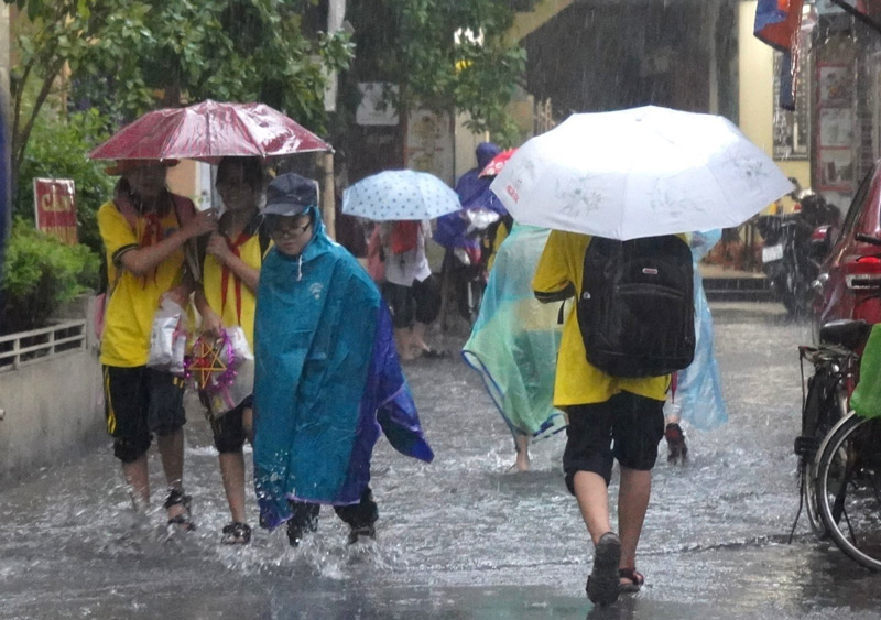Học sinh trường Tiểu học Võ Thị Sáu lội qua ngõ ngập nước để về nhà sau buổi học sáng. Ảnh: Mai Dung
