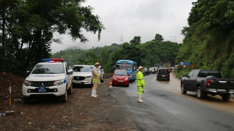 Lực lượng Cảnh sát giao thông phân luồng giao thông tại các vị trí sạt lở trên Quốc lộ 6, đoạn qua Dốc Cun. Ảnh: Minh Nguyễn