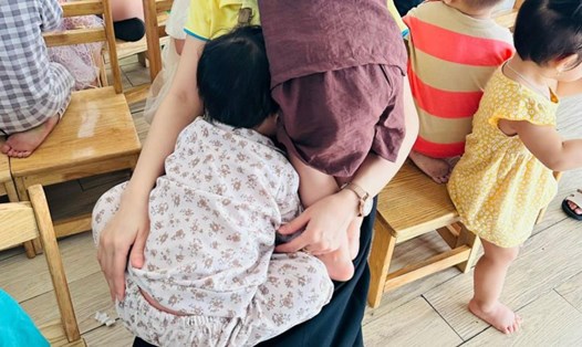 Em bé oà khóc trong vòng tay mẹ khi xem múa lân Tết Trung thu ở trường. Ảnh: Phụ huynh cung cấp