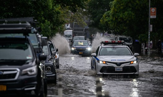 Các phương tiện di chuyển qua vùng nước lũ ở Brooklyn, New York, Mỹ ngày 29.9.2023. Ảnh: AFP