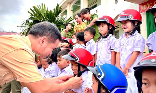 Chú CSGT tặng mũ bảo hiểm cho các bé trong ngày khai giảng. Ảnh: Cục CSGT