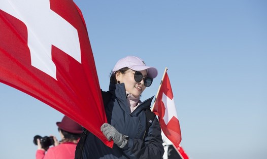 Du khách cầm cờ Thụy Sĩ ở vùng Interlaken. Ảnh: Xinhua 