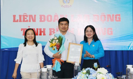 Lãnh đạo LĐLĐ tỉnh Bình Dương trao quyết định và tặng hoa chúc mừng ông Nguyễn Tấn Đạt. Ảnh: Hoàng Trung