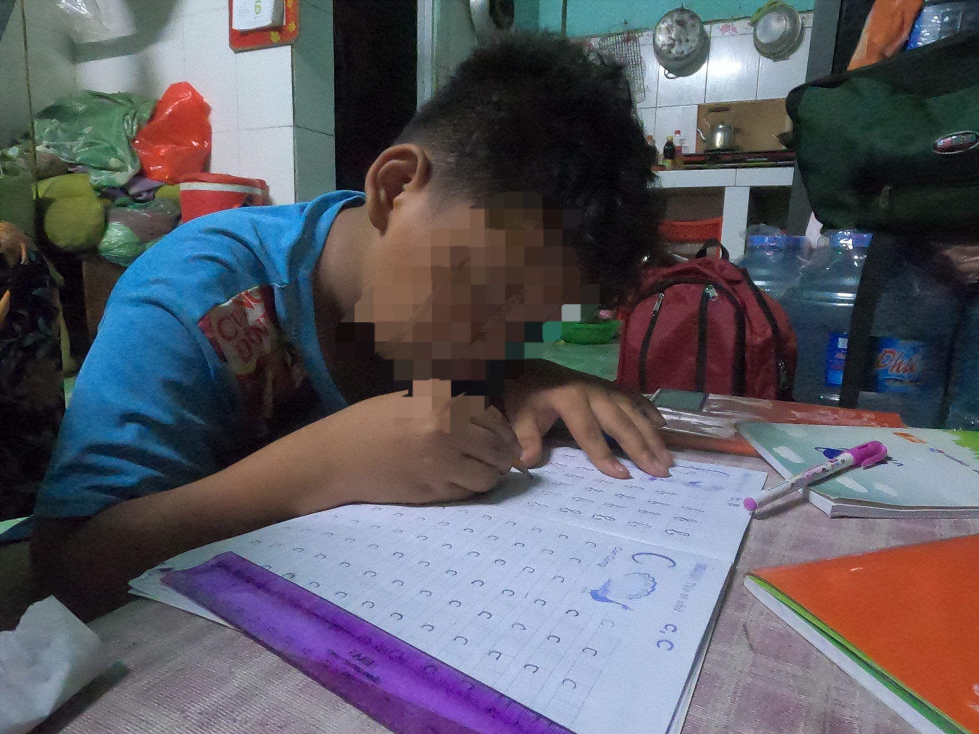 N.H.B đã 12 tuổi nhưng sẽ đi học trở lại từ lớp 1, em đang cố gắng tập viết và tô các chữ cái. Ảnh: Đình Trọng