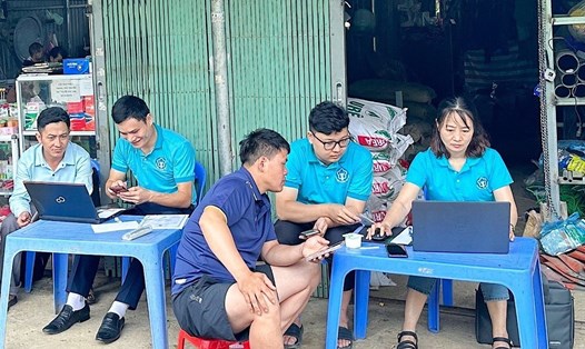 Cán bộ BHXH huyện Bảo Thắng hướng dẫn người dân cài đặt ứng dụng VssID. Ảnh: Hằng Quang