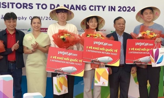 Du khách nước ngoài hào hứng khi được tặng nón lá tại sân bay Đà Nẵng. Ảnh: Trần Thi