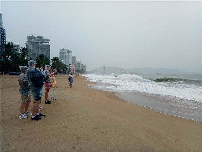 Khách du lịch đội mưa, chụp hình sóng lớn trên biển Nha Trang năm 2019. Ảnh: Phương Linh