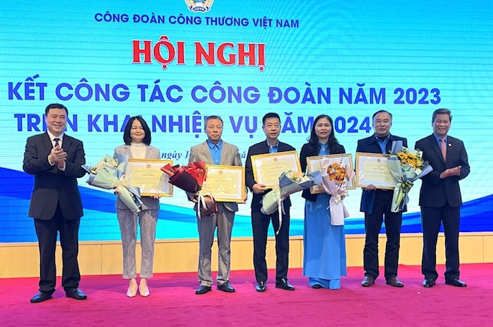 Phó Chủ tịch Tổng LĐLĐVN Huỳnh Thanh Xuân và Thứ trưởng Bộ Công Thương Nguyễn Sinh Nhật Tân tặng Bằng khen của Tổng LĐLĐVN và hoa cho các tập thể thuộc Công đoàn Công Thương Việt Nam. Ảnh: Hà Anh