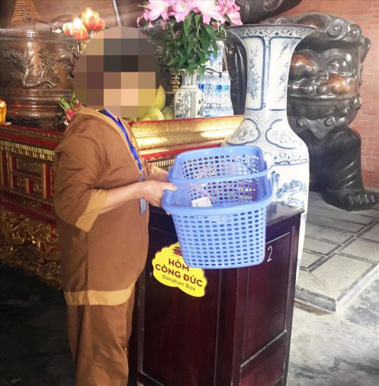 Một nhân viên ở ngôi chùa lớn trên địa bàn tỉnh Ninh Bình gom tiền đặt ở các ban thờ, bỏ vào thùng công đức. Ảnh: Nguyễn Trường