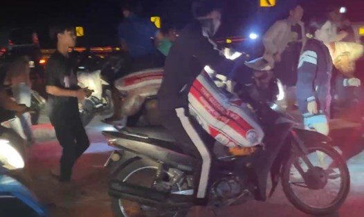 Một người dùng xe môtô chở các bao gạo nếp lấy từ xe ôtô tải bị lật. Ảnh: Tạo Nguyễn.