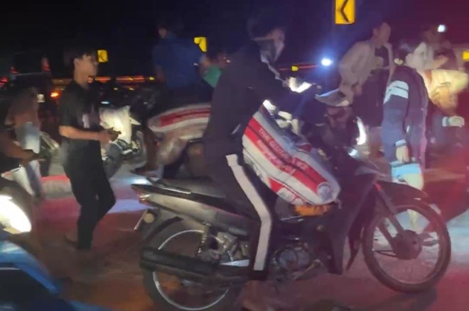 Một người dùng xe môtô chở các bao gạo nếp lấy từ xe ôtô tải bị lật. Ảnh: Tạo Nguyễn.