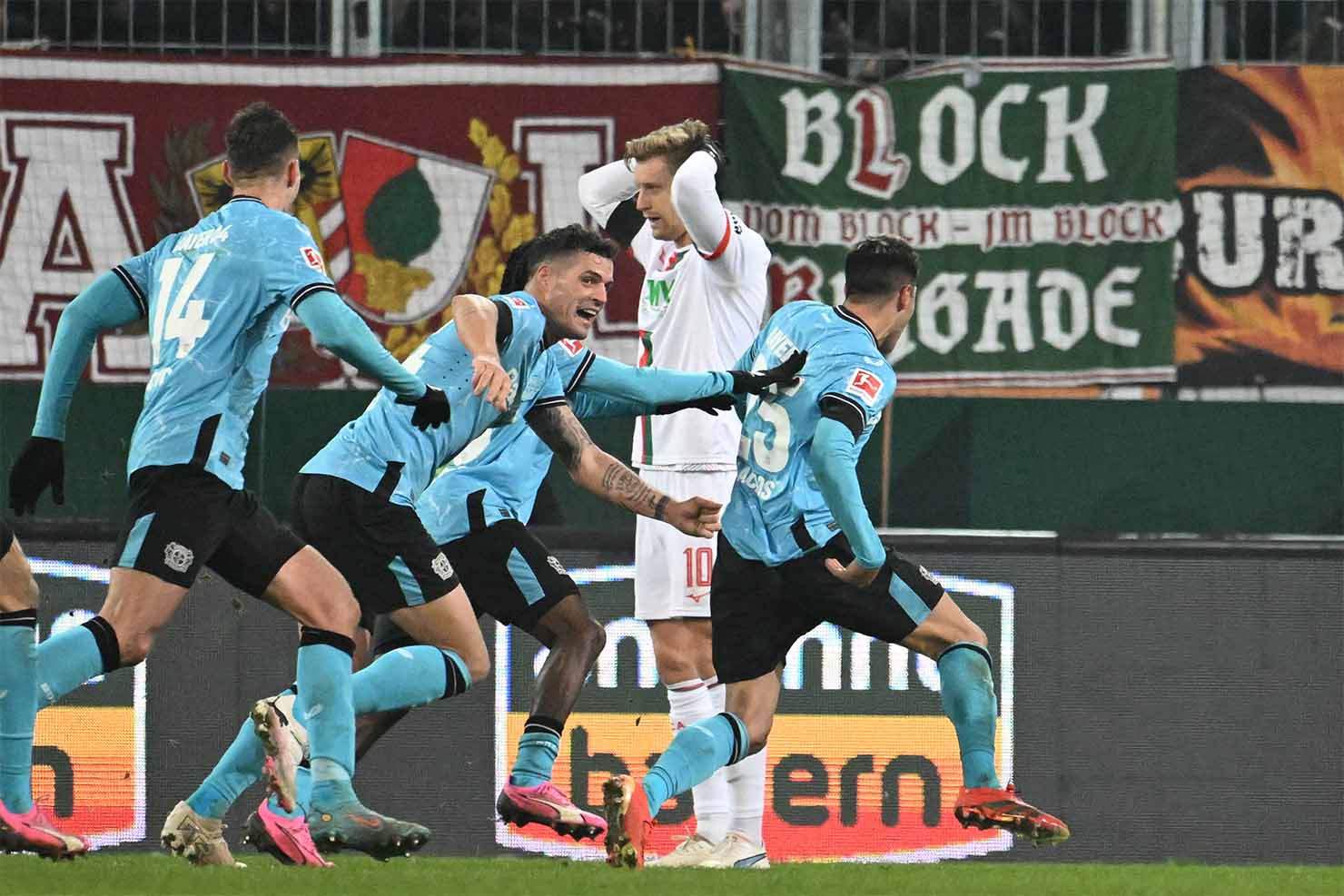 Các cầu thủ Bayer Leverkusen ăn mừng cuồng nhiệt khi ghi bàn thắng ấn định tỉ số 1-0 trước Augsburg vào phút 90+4. Ảnh: AFP