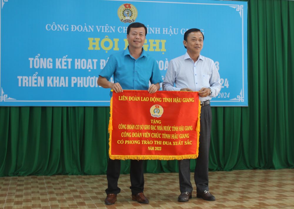 Ông Lê Công Khanh (bìa phải), Chủ tịch Liên đoàn Lao động tỉnh, trao Cờ thi đua năm 2023 của Liên đoàn Lao động tỉnh cho đại diện Công đoàn cơ sở Kho bạc nhà nước tỉnh. Ảnh: Tạ Quang