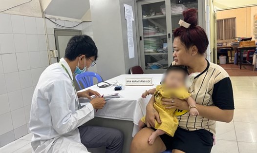 Phụ huynh đưa con đi tiêm vaccine TCMR. Ảnh: Nguyễn Ly