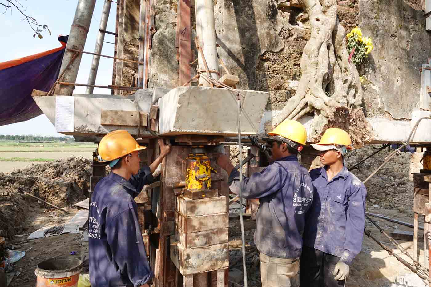 Nhóm thợ đang đổ bê tông vào một trụ sắt đã đóng ván cốp pha để hoàn thành trụ cổng đền cao 1,2m. Ảnh: Trần Tuấn.