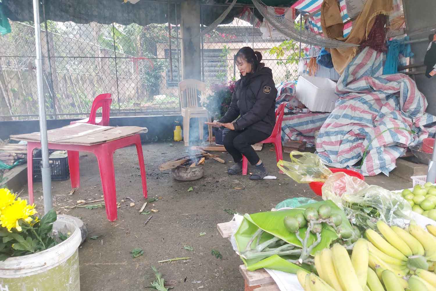 Người phụ nữ này ở thôn Tân Hòa, xã Tân Lâm Hương cũng đốt lửa sưởi ấm trong lúc bán hàng. Ảnh: Trần Tuấn.