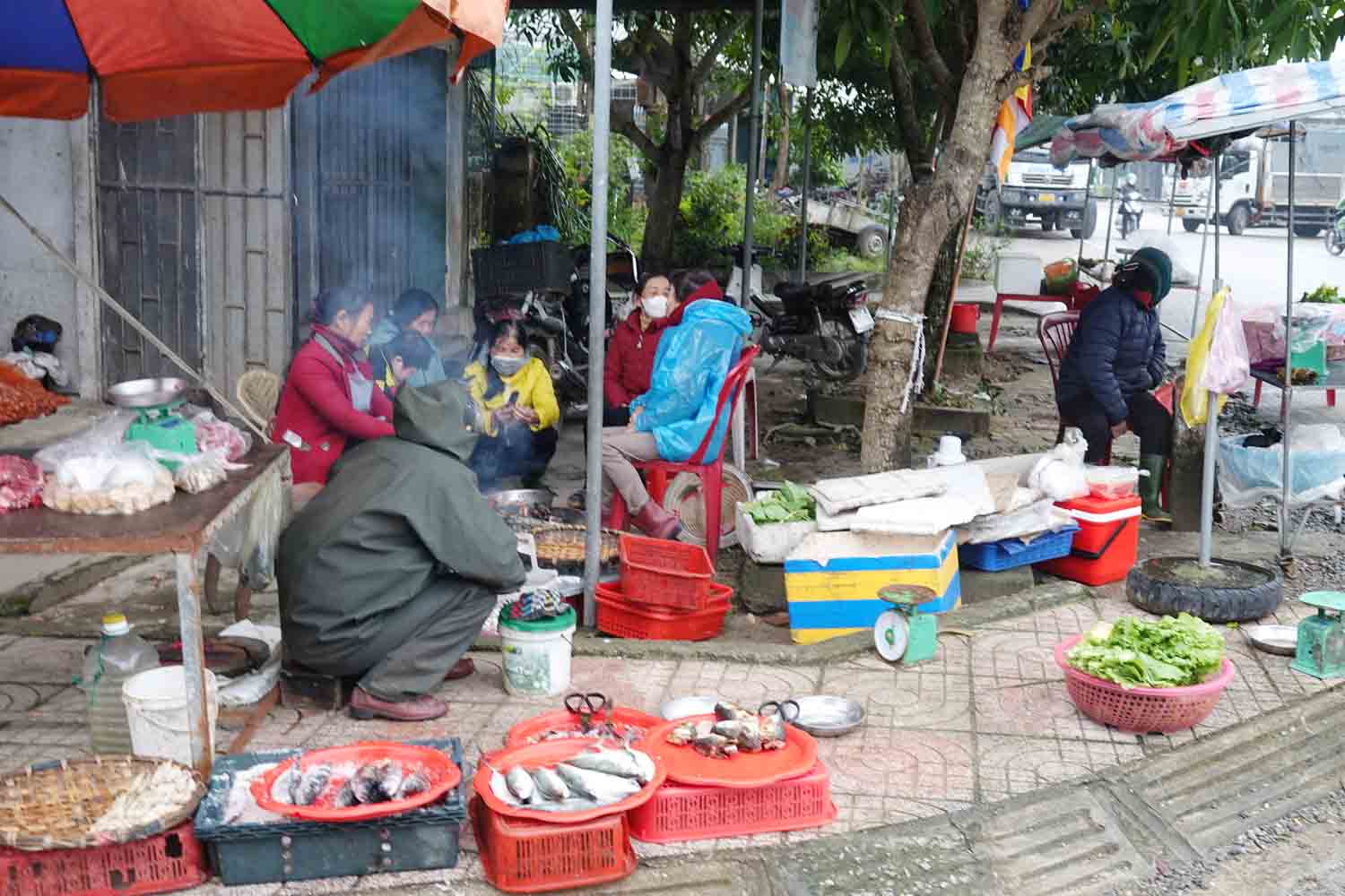 Nhiều phụ nữ bán hàng rong bên tỉnh lộ 553 (thuộc thôn La Xá, xã Tân Lâm Hương, huyện Thạch Hà) đang quây quần bên bép lửa vừa sưởi ấm vừa bán hàng. Ảnh: Trần Tuấn.