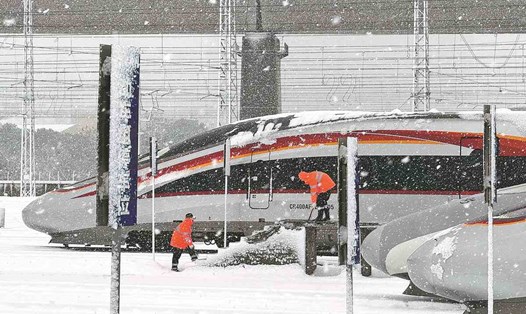 Công nhân dọn tuyết và băng khỏi tàu cao tốc tại một nhà ga ở Nam Xương, tỉnh Giang Tây, Trung Quốc, ngày 22.1.2024. Ảnh: China Daily