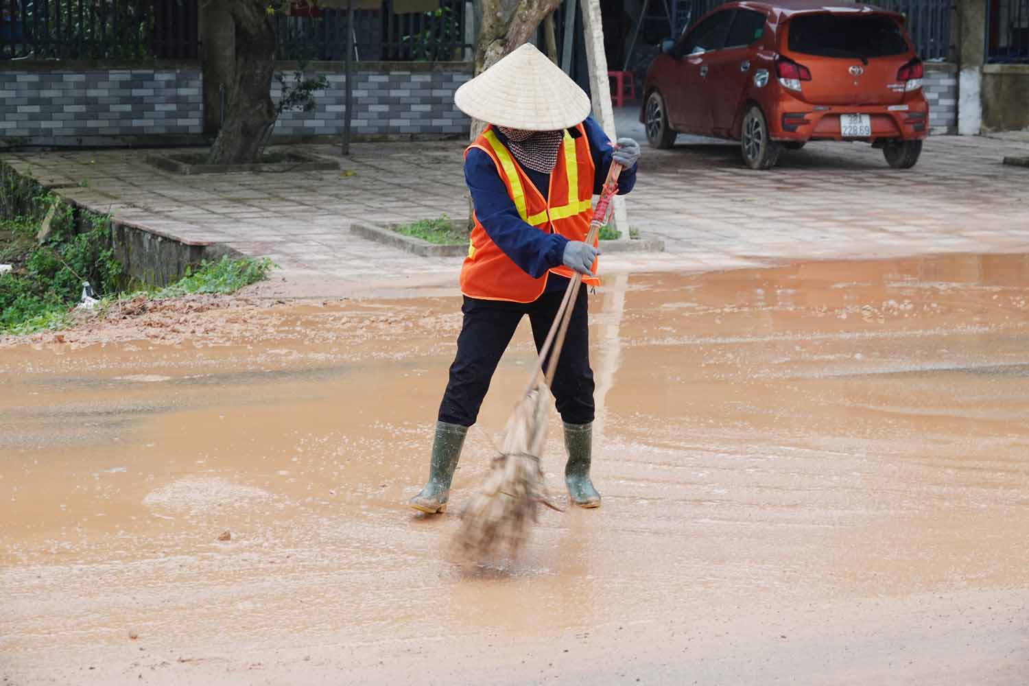 Cùng với xe bồn tưới nước, công nhân dùng chổi quét bùn đất vương trên đường. Ảnh: Trần Tuấn.