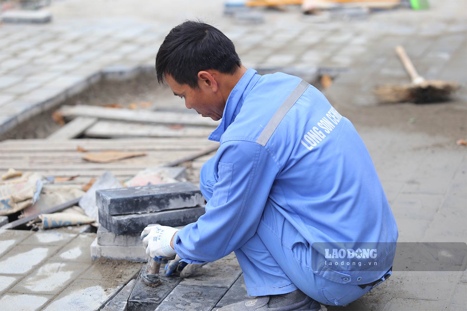 Công nhân làm việc xuyên trưa để kịp hoàn thiện lát đá vỉa hè trước ngày 16.1. Ảnh: Vĩnh Hoàng