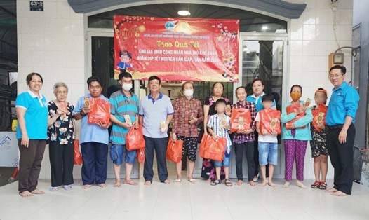 Đại diện các gia đình công nhân, NLĐ ở trọ nhận quà Tết do bà Nguyễn Thị Tuyết Thương (bìa trái) trao tặng. 
Ảnh: Đức Long