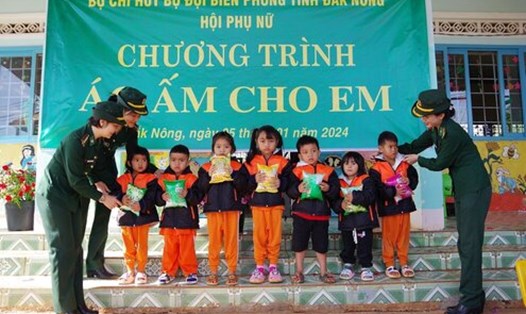 Đại diện Hội Phụ nữ Bộ đội Biên phòng  tỉnh Đắk Nông trao áo ấm cho các em nhỏ ở khu vực biên giới. Ảnh: Văn Hoàn