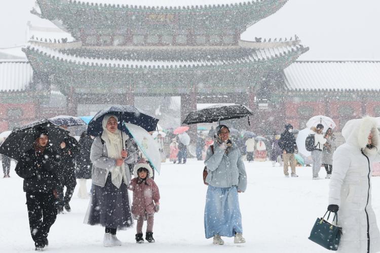 Người dân và du khách đi bộ trước cổng cung Gyeongbok, phía bắc thủ đô Seoul của Hàn Quốc dịp tuyết rơi dày kỷ lục vào ngày cuối cùng năm 2023. Ảnh: Yonhap 