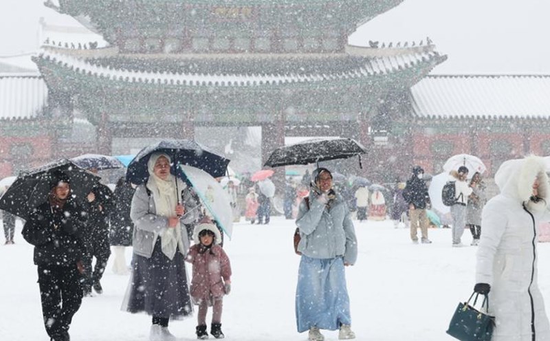 Người dân và du khách đi bộ trước cổng cung điện Gyeongbok, trung tâm thủ đô Seoul Hàn Quốc trong tiết trời tuyết rơi dày kỷ lục vào ngày cuối cùng năm 2023. Ảnh: Yonhap