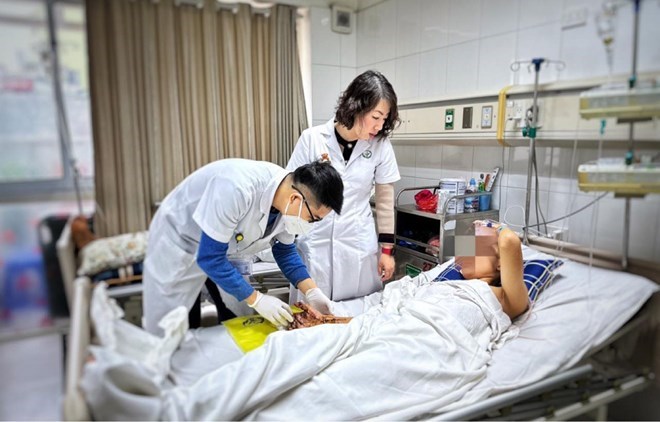 Các bác sĩ Bệnh viện Hữu nghị Việt Đức thăm khám cho bệnh nhân bị dập nát tay do pháo tự chế. Ảnh: Bệnh viện cung cấp 