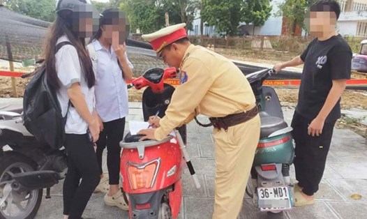 Lực lượng CSGT Thanh Hóa kiểm tra, xử phạt học sinh đi xe máy khi chưa đủ điều kiện. Ảnh: CATH