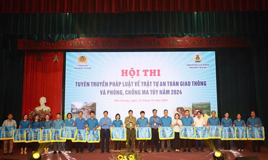 Lãnh đạo Liên đoàn Lao động tỉnh Bắc Giang, Công an tỉnh Bắc Giang trao cờ lưu niệm cho các đội tham dự hội thi tuyên truyền pháp luật về trật tự an toàn giao thông, phòng chống ma túy. Ảnh: Quyết Chiến