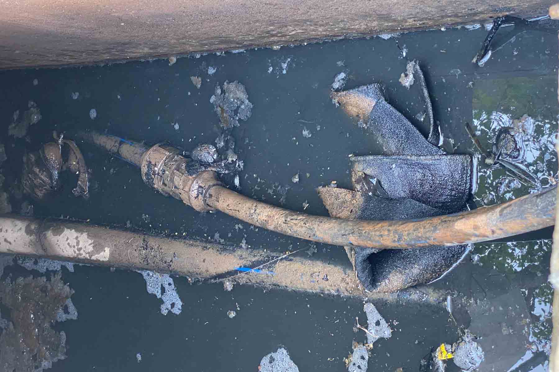 Đường ống nước sạch đặt trong lòng mương dẫn nước đen kịt khiến người dân thôn Phương Trứ lo ngại. Ảnh: Trần Tuấn