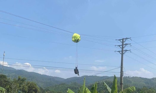 Hình ảnh người đàn ông cùng dù lượn mắc kẹt tại đường dây điện. Ảnh: Người dân cung cấp.