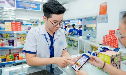 Nhân viên nhà thuốc đang hướng dẫn người dân cách sử dụng ứng dụng đặt mua thuốc. Ảnh: Thùy Linh