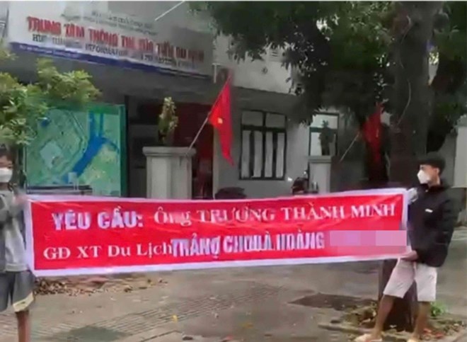 Image of two young men holding a banner demanding debt in front of the gate of the Tourism Promotion Information Center, belonging to the Department of Tourism of Thua Thien Hue province. Photo: Phuc Dat