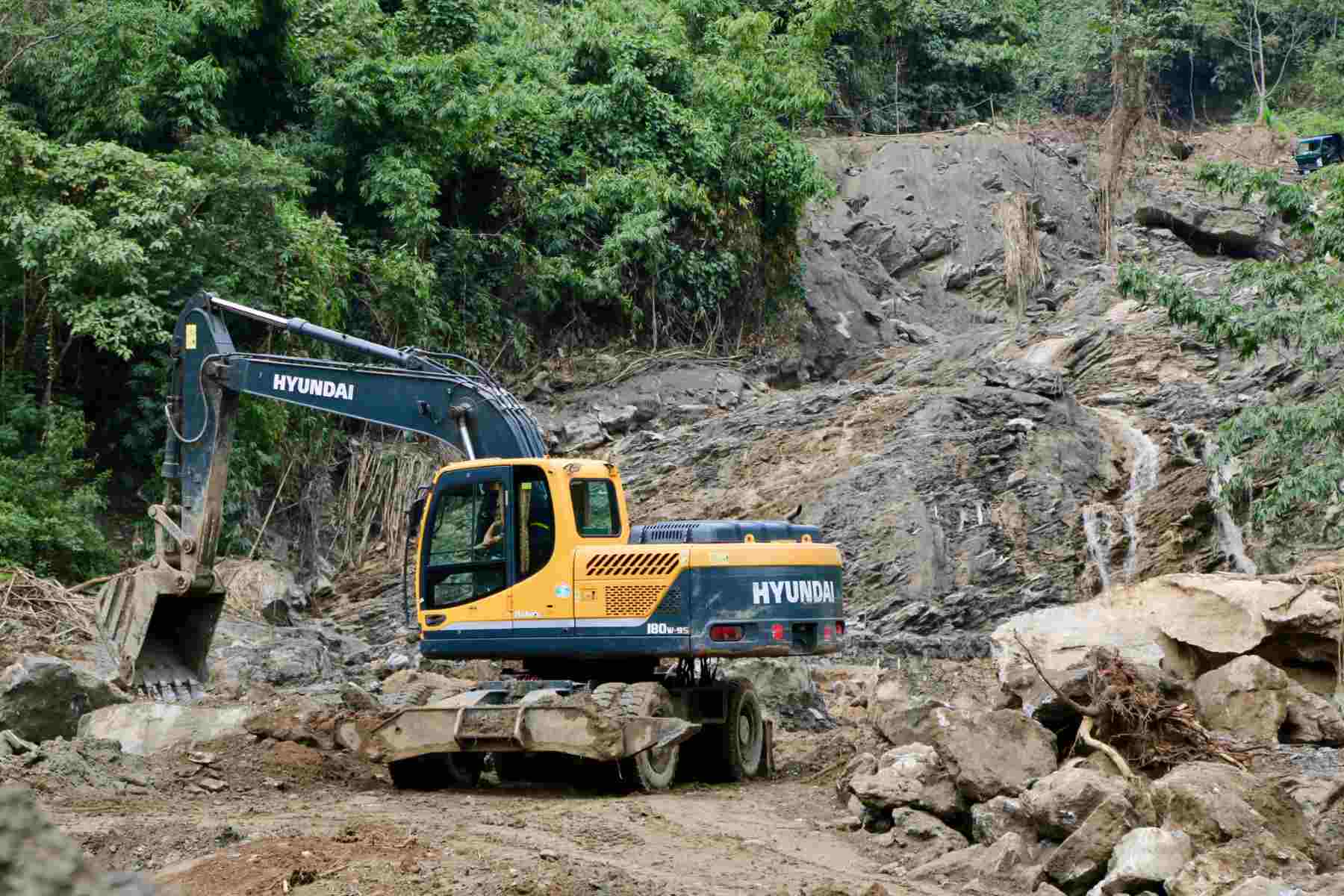 Máy móc vẫn đang thu dọn, xử lý điểm bị bùn thải tràn qua. Ảnh: Ngọc Minh