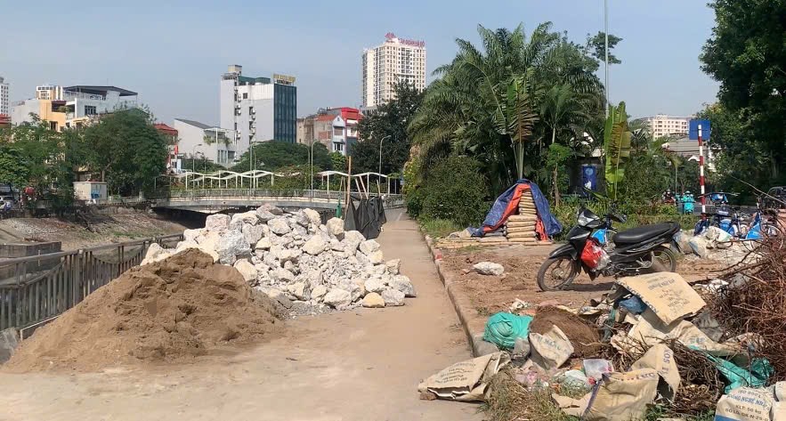 Construction materials are piled up haphazardly, narrowing the path for cyclists. Photo: Nhat Minh