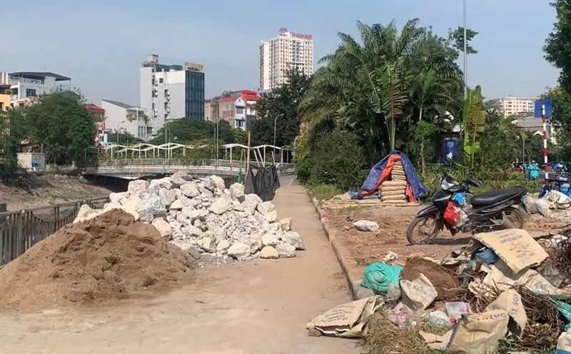 Construction materials are piled up haphazardly, narrowing the path for cyclists. Photo: Nhat Minh