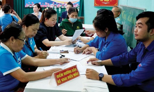 Hướng dẫn người dân kê khai biểu mẫu để nhận lương hưu, trợ cấp BHXH qua tài khoản ngân hàng. Ảnh: Thanh Hương