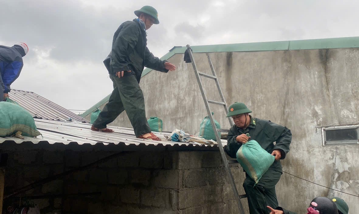 Border guards help people tie up their houses to cope with storm Tra Mi.