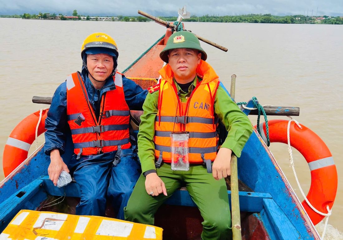 Dai uy Hoang Ngoc Minh (phai anh) di vao vung lu tren chiec thuyen cua ngu dan xa Vinh Thai. Anh: H.Nguyen.